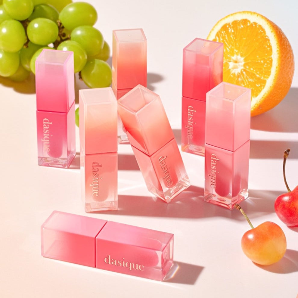 Collection of DASIQUE Juicy Dewy Tint products with vibrant fruit accents in the background.