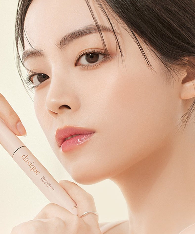 Close-up of woman holding DASIQUE Mood Up Mascara Long & Curl, showcasing the product's elegant packaging.