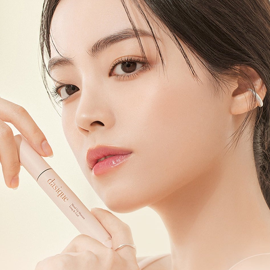 Close-up of woman holding DASIQUE Mood Up Mascara Long & Curl, showcasing the product's elegant packaging.
