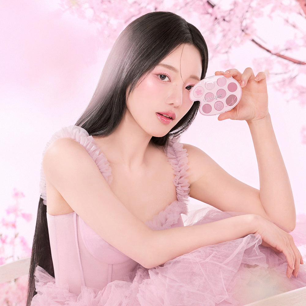 Model holding DASIQUE Pink Blossom Shadow Palette in front of cherry blossom background.