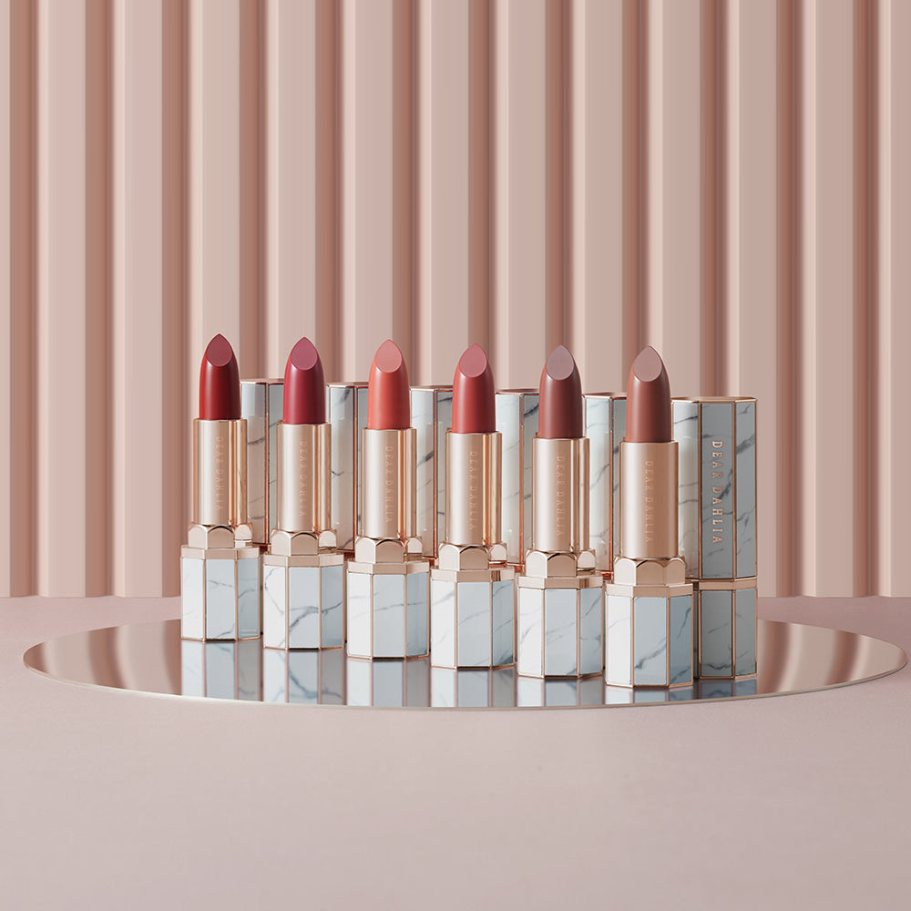 Collection of DEAR DAHLIA Lip Paradise Sheer Dew Lipstick in various shades, displayed elegantly on a reflective surface.