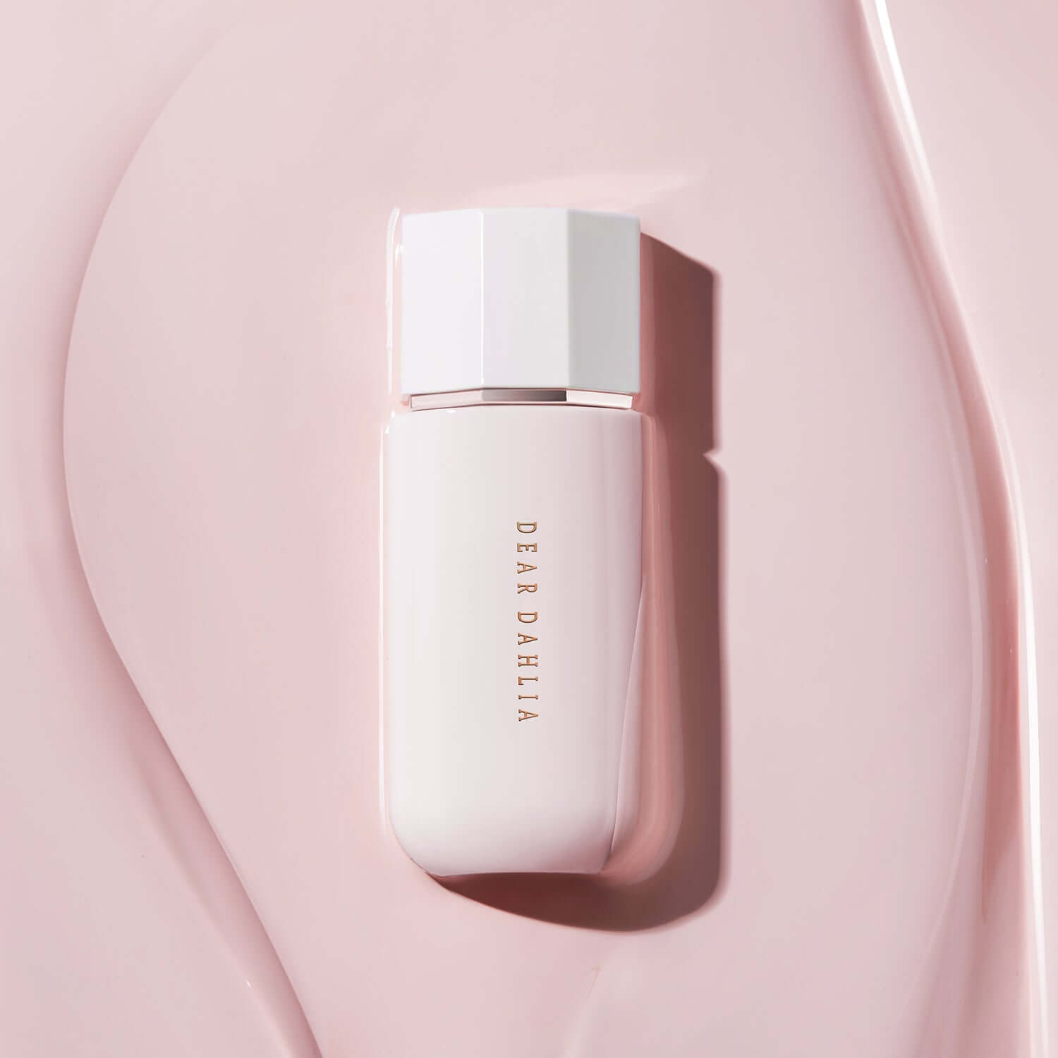 DEAR DAHLIA Prime Layer Glow Primer bottle on pink surface