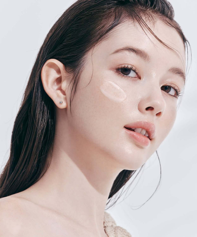 Model applying DEAR DAHLIA Prime Layer Skin Prep on cheek for smooth, radiant finish.