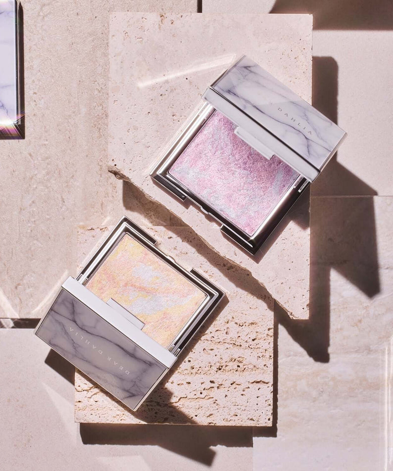 Open DEAR DAHLIA Skin Luminous Highlighter compacts on a beige geometric surface