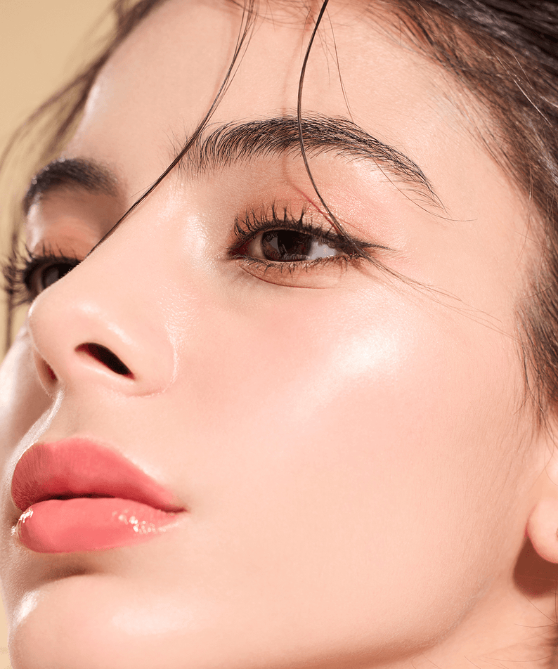 Woman with radiant skin using DEAR DAHLIA Skin Luminous Highlighter for a glowing look.