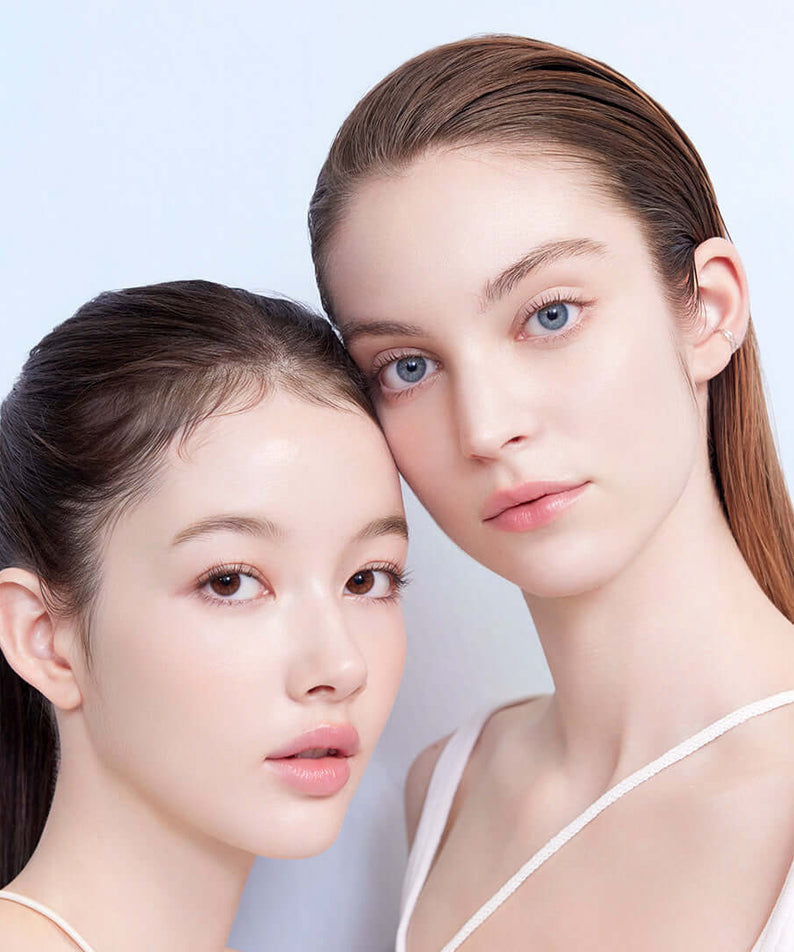 Two models showcasing the benefits of DEAR DAHLIA Sun Breeze Hydro Sun Lotion on their flawless skin.