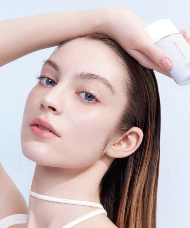 Model holding DEAR DAHLIA Sun Breeze Hydro Sun Lotion, showcasing its packaging and texture.