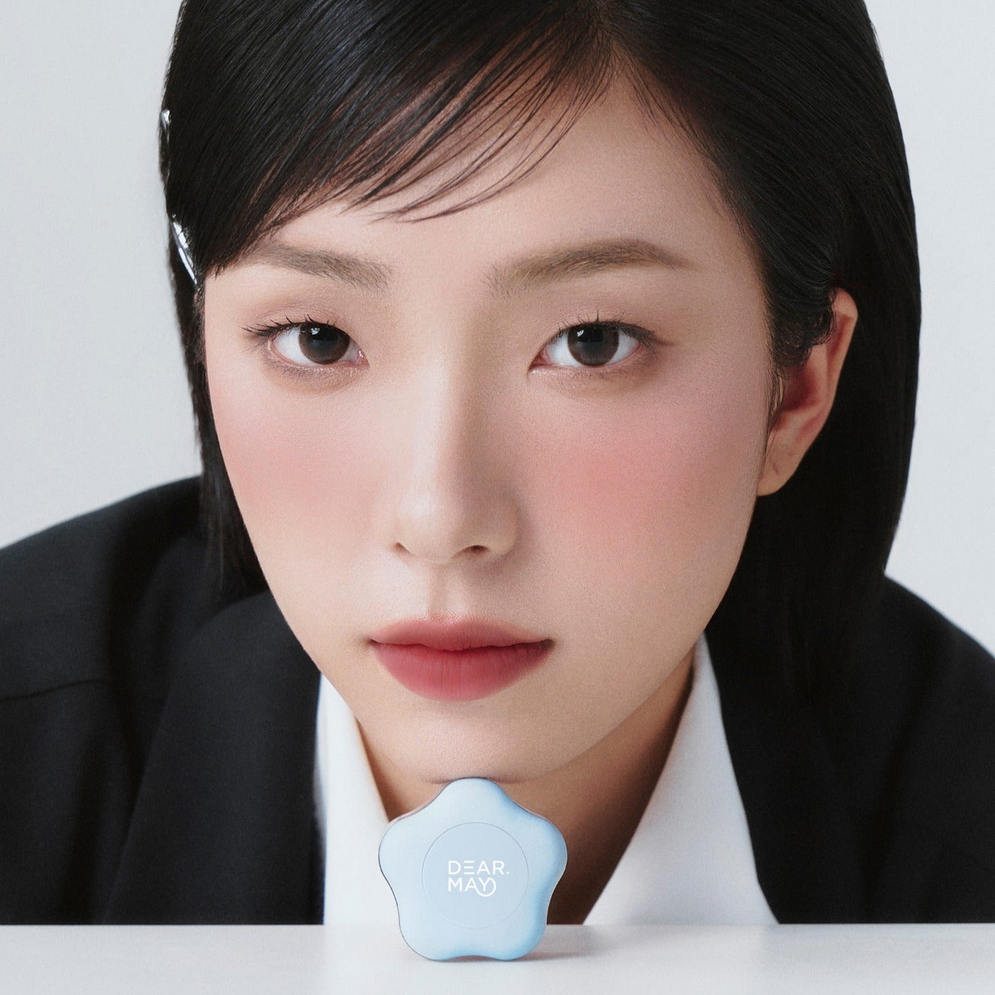 A close-up of a person showcasing DEAR MAY Pure Falling Mood Lip Pot 6.5g with a blue container in front.