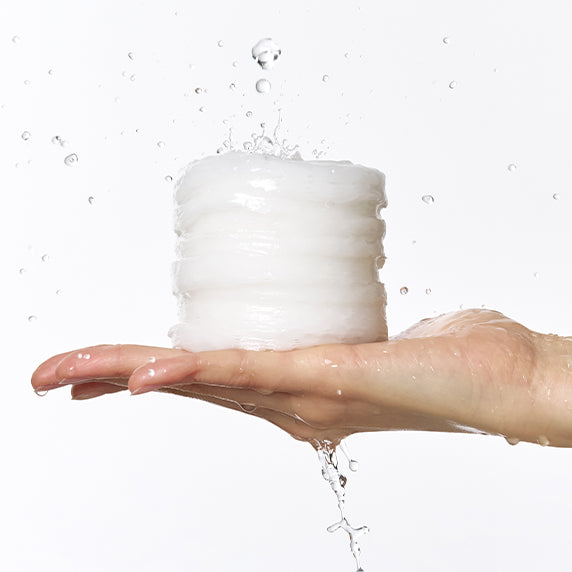 Hand holding DERMATORY Hyaluronic Moisture Embo Pad 60 pads with water splashes