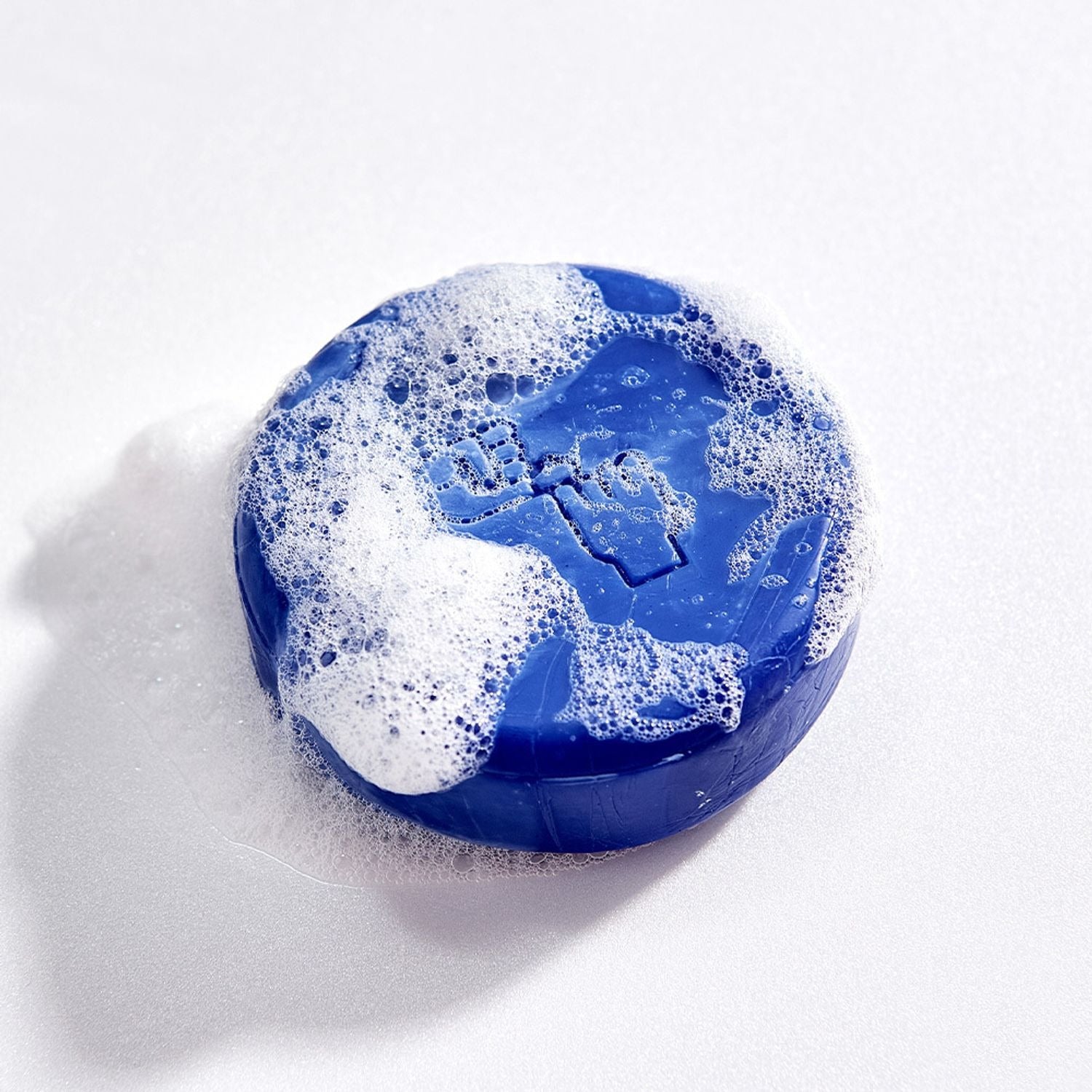 DONGGUBAT Correct Shampoo Bar Cooling with bubbles, blue round soap bar on white background