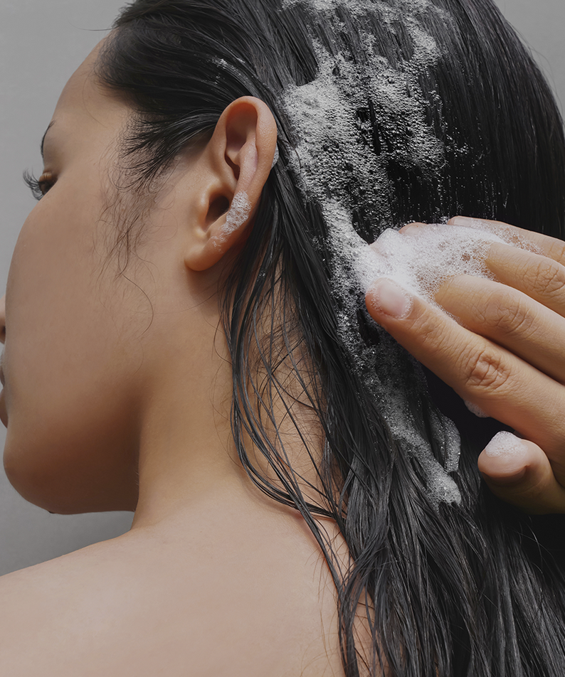 Person using DONGGUBAT Correct Shampoo Bar For Dry Skin on wet hair, creating a lather, highlighting its benefits for dry scalp care.