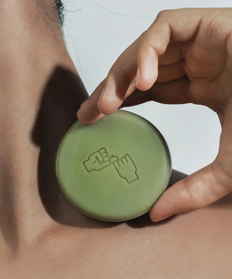DONGGUBAT Correct Shampoo Bar For Dry Skin displayed on a person's neck, showcasing its natural green color and embossed design.