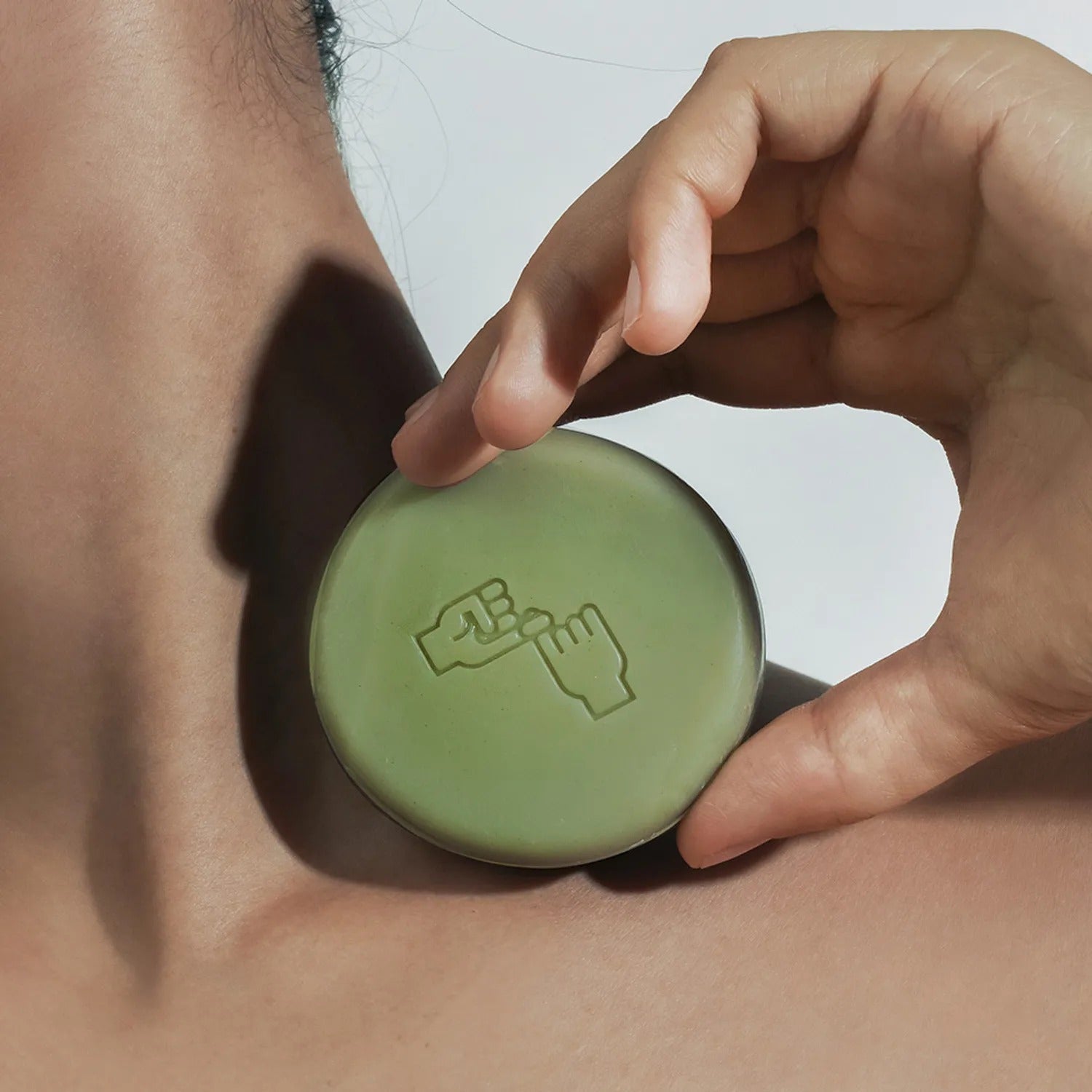 DONGGUBAT Correct Shampoo Bar For Dry Skin displayed on a person's neck, showcasing its natural green color and embossed design.