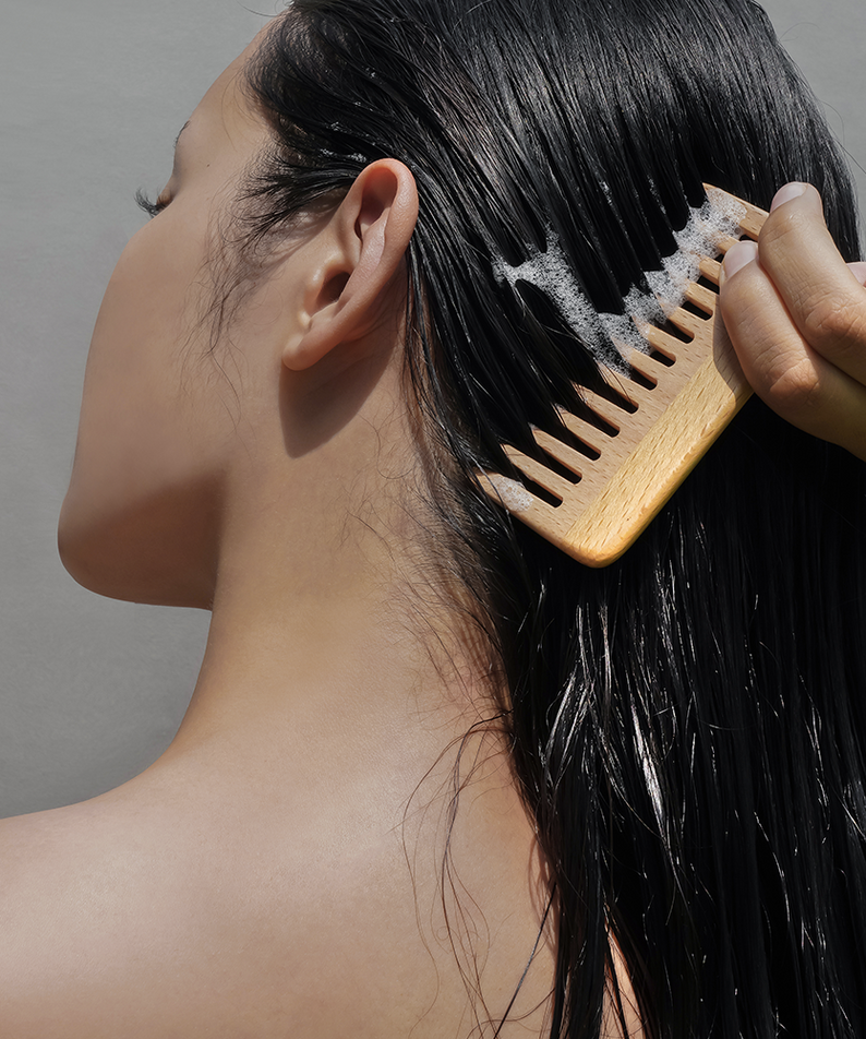 Woman using DONGGUBAT Correct Shampoo Bar For Oily Skin, lathered hair combed with a wooden comb