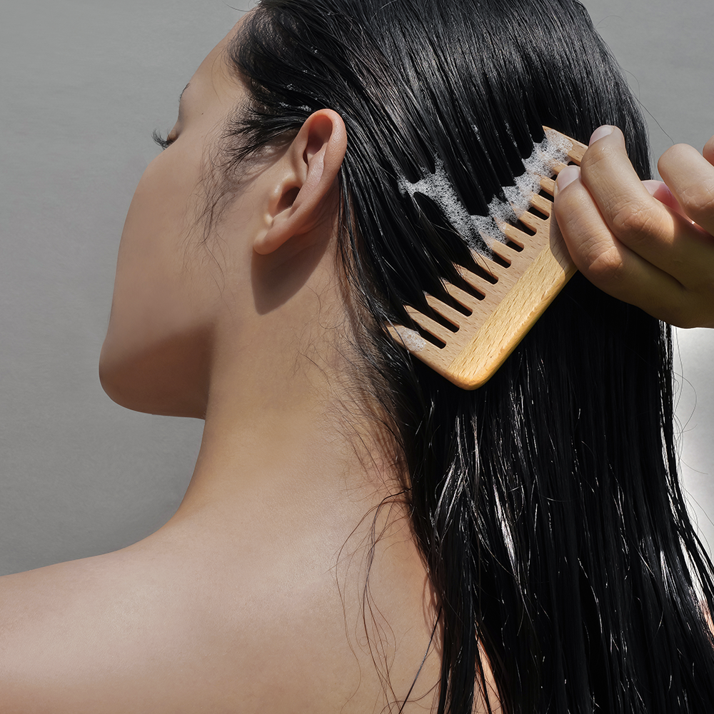 Woman using DONGGUBAT Correct Shampoo Bar For Oily Skin, lathered hair combed with a wooden comb