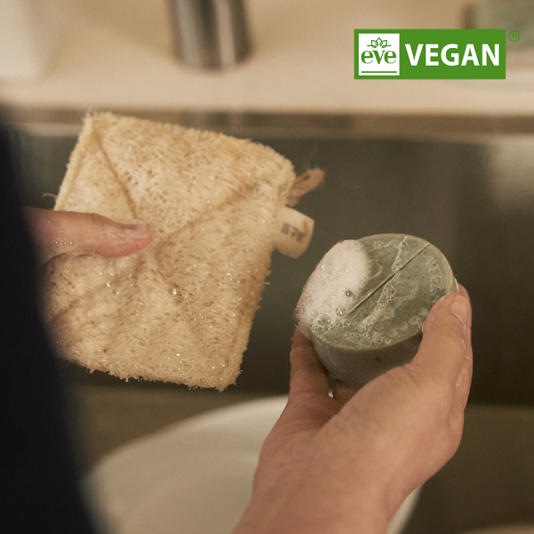 DONGGUBAT Vegan Dishwashing Soap Green Tea 100g in use with a natural sponge in a kitchen setting, eco-friendly cleaning product.