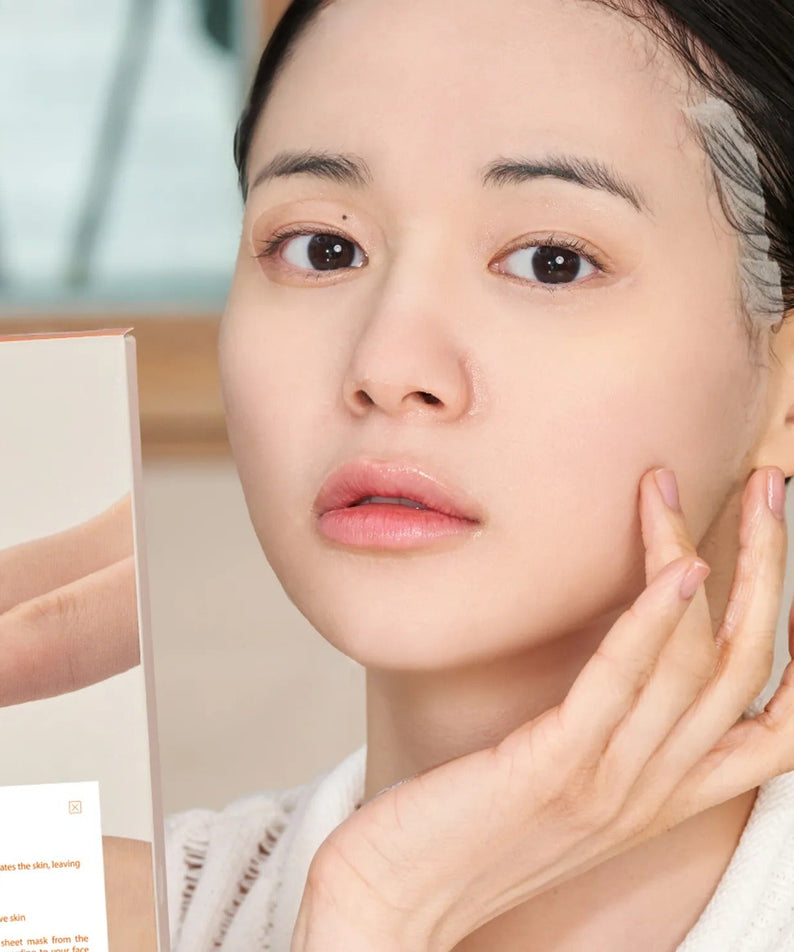 Person holding DR.ALTHEA Vita glow Mask (4ea) and touching face, depicting skincare routine and product application.