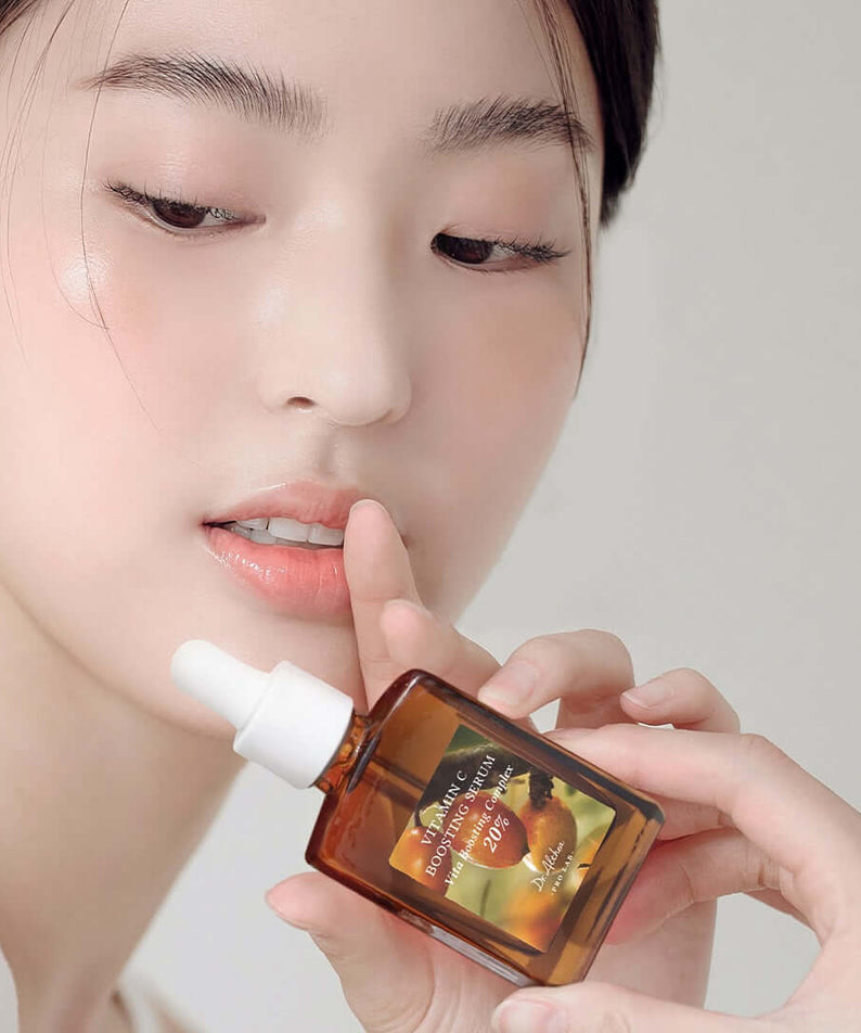 Person holding DR.ALTHEA Vitamin C Boosting Serum 30ml bottle near face.