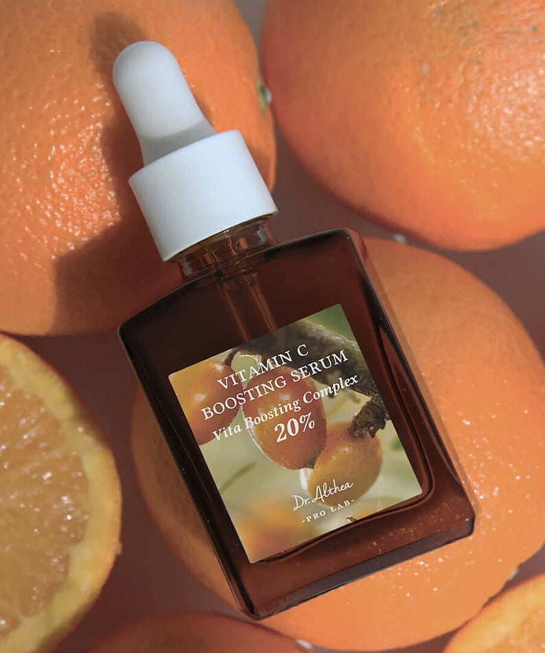 DR.ALTHEA Vitamin C Boosting Serum 30ml with dropper surrounded by fresh oranges, highlighting citrus ingredients for radiant skin.