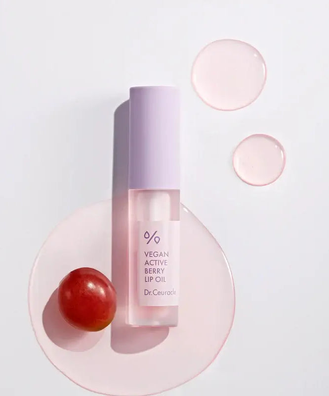 DR.CEURACLE Vegan Active Berry Lip Oil with grape and oil droplets on a white background