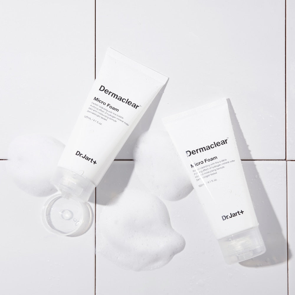 Two tubes of DR.JART+ DermaClear Micro Foam 120ml on a tiled surface with foamy bubbles.