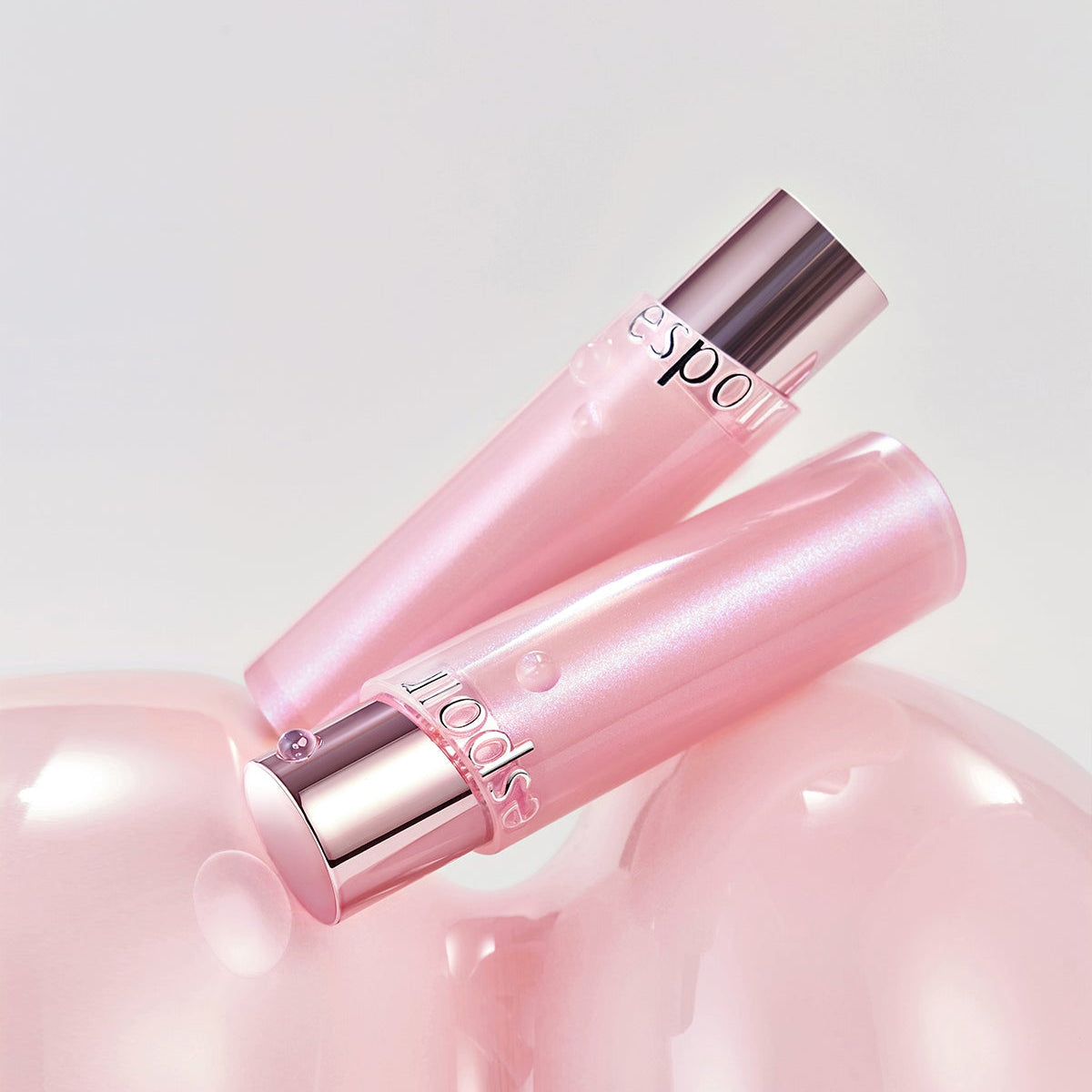 ESPOIR Bare Glow Lip Balm in pink packaging on a glossy surface, showcases luxurious and moisturizing qualities.