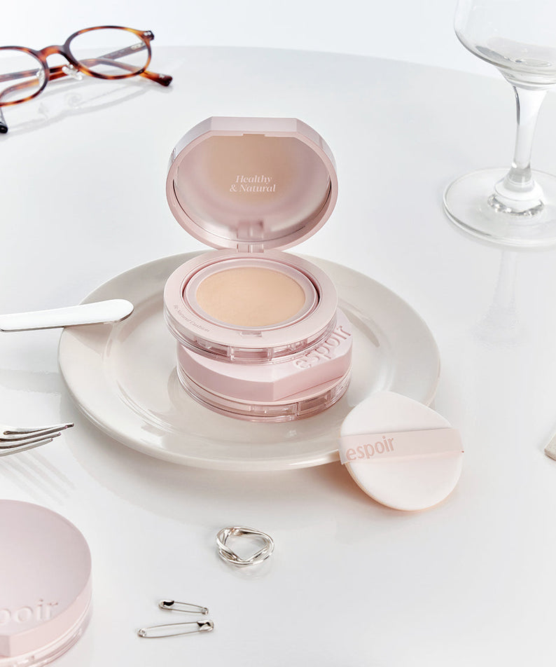 ESPOIR Be Natural Cushion SPF50+ PA++++ compact on a plate with accessories, highlighting its premium skincare and makeup benefits.