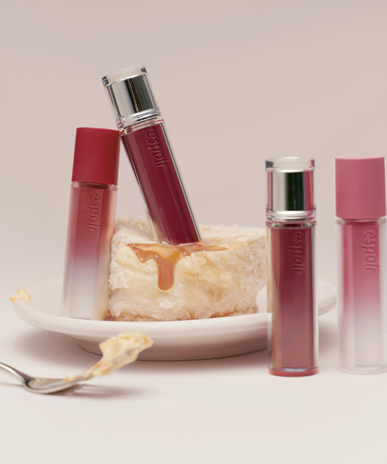 ESPOIR Couture Lip Tint Glaze [NEW COLOR] tubes displayed innovatively with dessert background, showcasing the new color variant.
