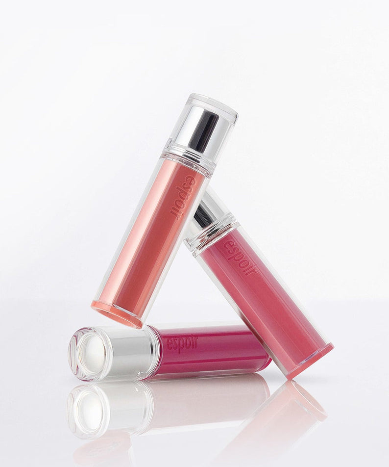 ESPOIR Couture Lip Tint Glaze in three shades, showcasing elegant packaging on a reflective surface.