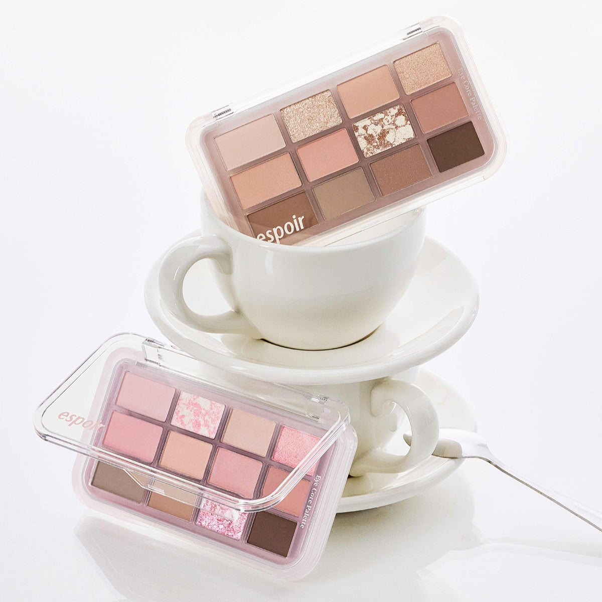 ESPOIR Eye Core Palette featuring a collection of warm and pink eyeshadows displayed on a stack of white teacups.