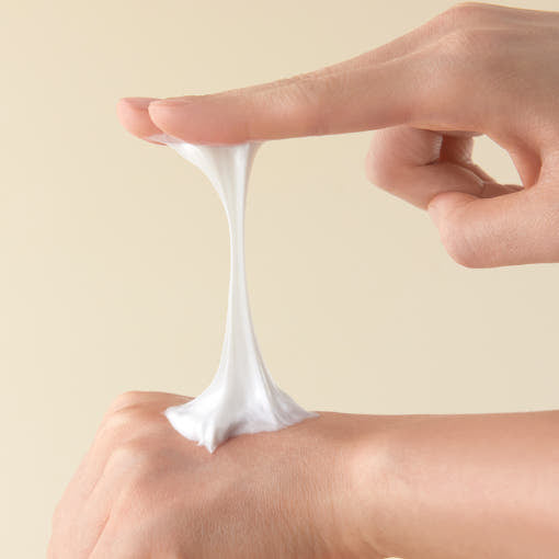 Texture of ESSENHERB Black Snail Signature Lift Cream 50ml being stretched between fingers and hand.