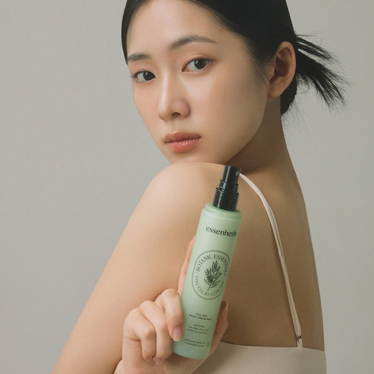 Woman holding a bottle of ESSENHERB Tea Tree Body Cream Mist 130ml, highlighting skincare benefits.