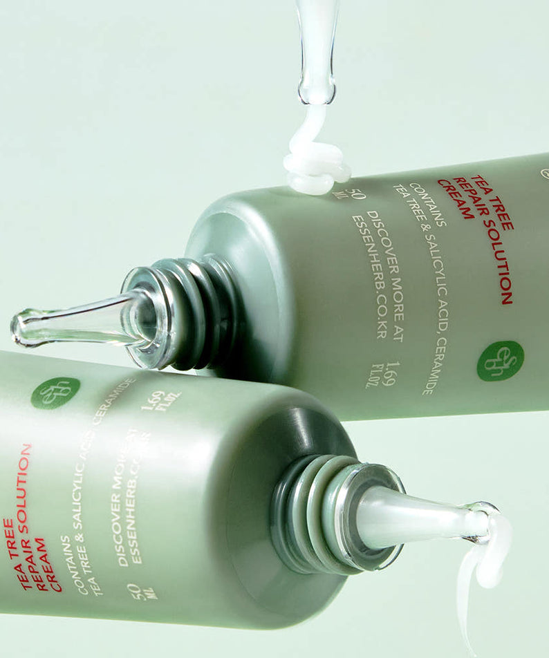ESSENHERB Tea Tree Repair Solution Cream 50ml bottles dispensing product on green background