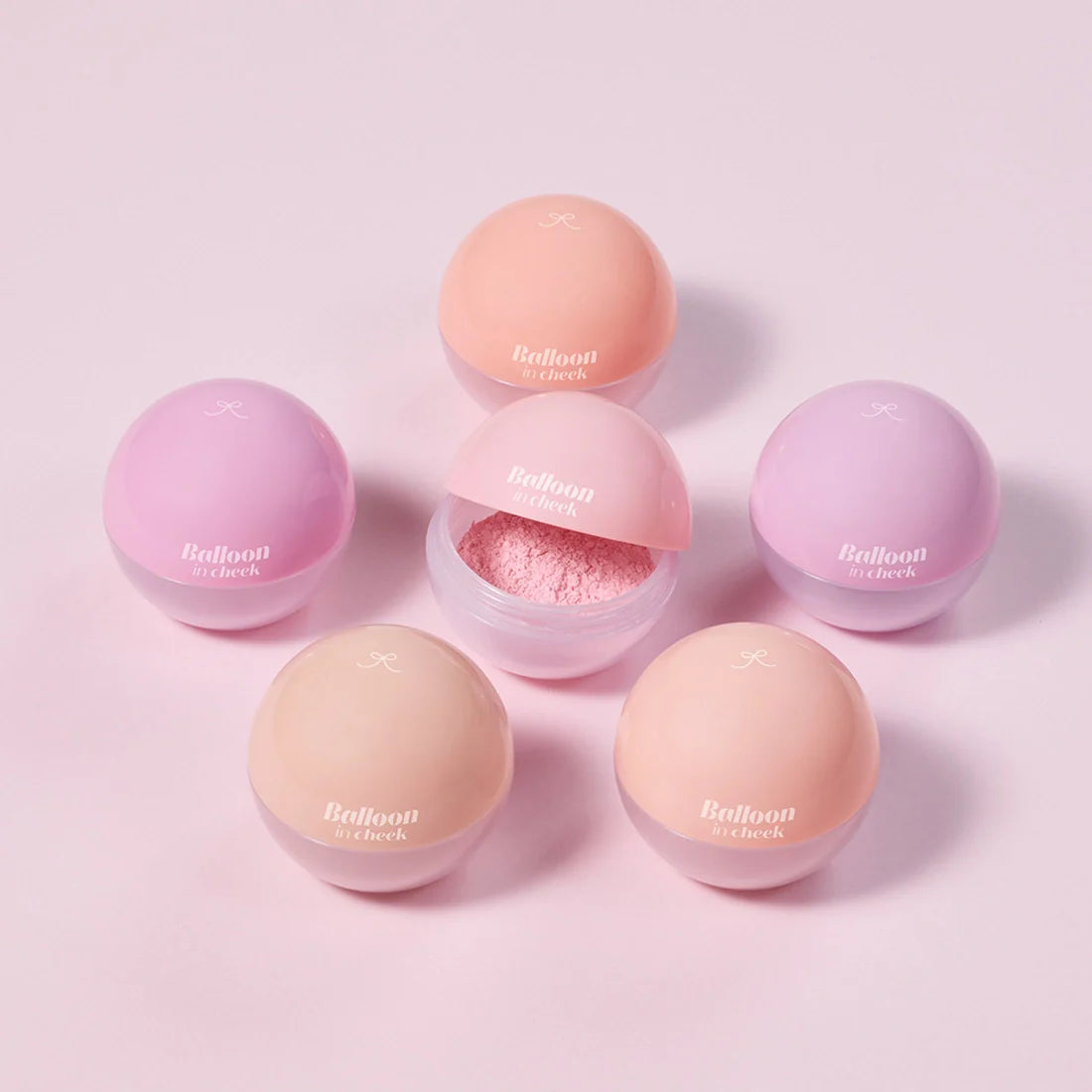 Assorted ETUDE Balloon in cheek 6g blush shades in spherical containers on a pink background.