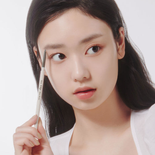 Woman using ETUDE Bare Edge Slim Brow Pencil to shape eyebrows with precision.