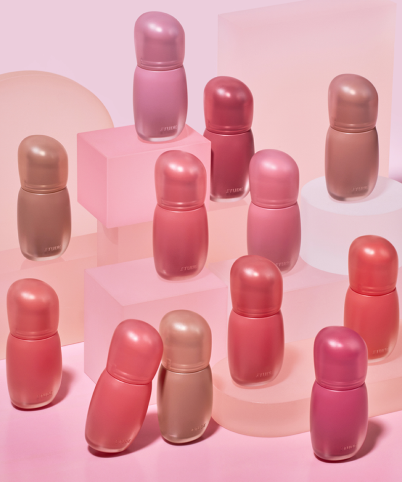 Assorted shades of ETUDE Cozy Fixing Tint 4g bottles on a pink background.
