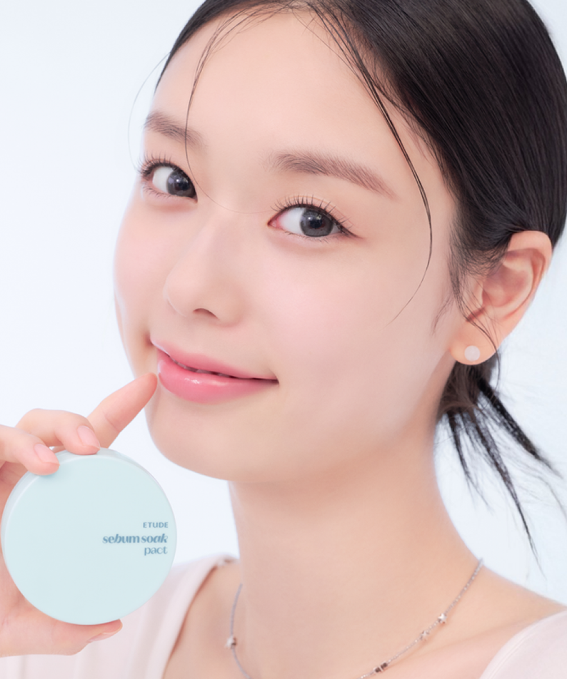 Close-up of a person holding ETUDE Fiji Ssok Pact 9.5g next to their face, showcasing its packaging and potential usage.