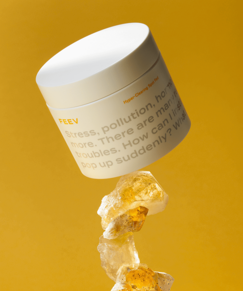 FEEV Hyper-Clearing Spot Pads 100ml on display with a background of golden stones and a vibrant yellow backdrop.
