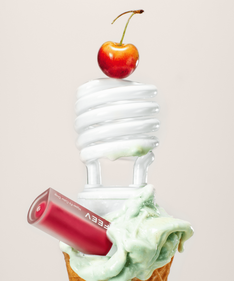 FEEV Hyper-Fit Color Drop Tint with light bulb and cone, featuring vibrant cherry on top, ideal for radiant makeup looks.