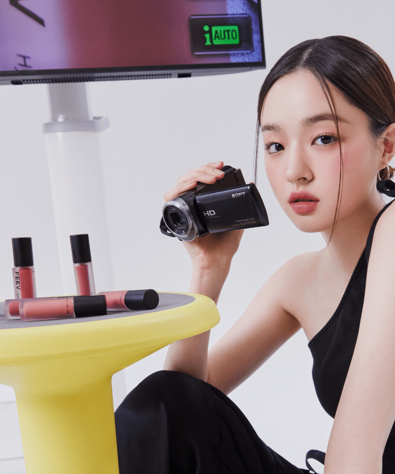 FEEV Hyper-Fit Color Wear Tint displayed with a model holding a camera, showcasing makeup application and style.