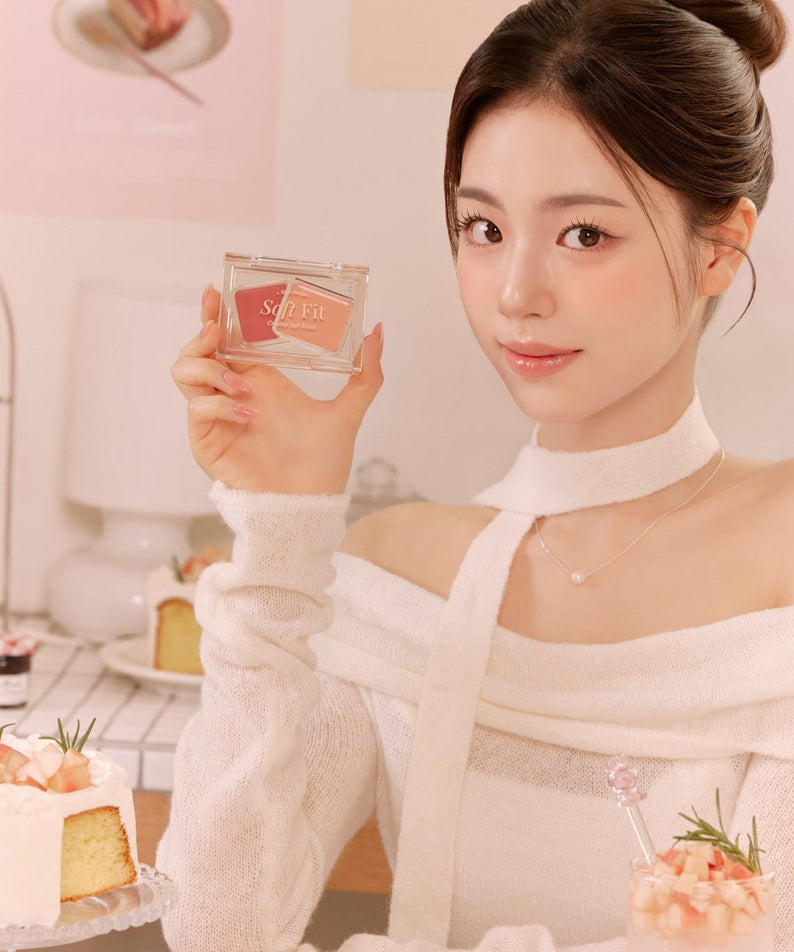 Person holding FORENCOS Soft Fitting Cream Blusher near cakes in cozy setting.