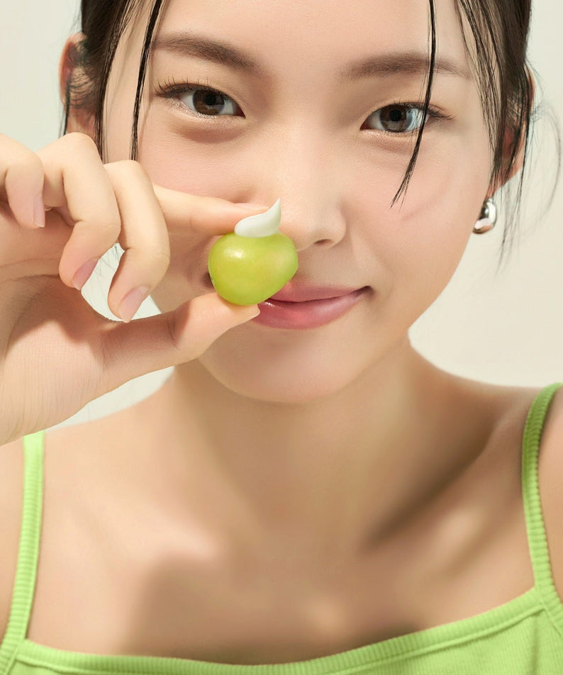 Woman holding skincare representing FRUDIA Avocado Greenery Relief Sun Cream 50g
