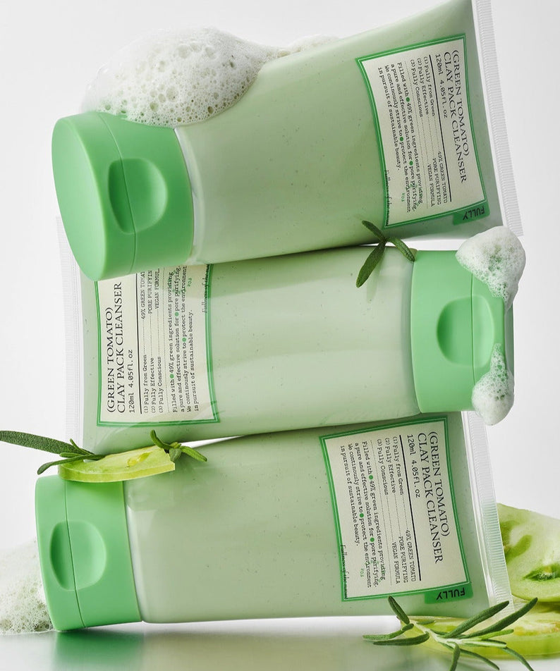 FULLY Green Tomato Clay Pack Cleanser 120ml bottles with green caps, surrounded by fresh rosemary and tomato slices.