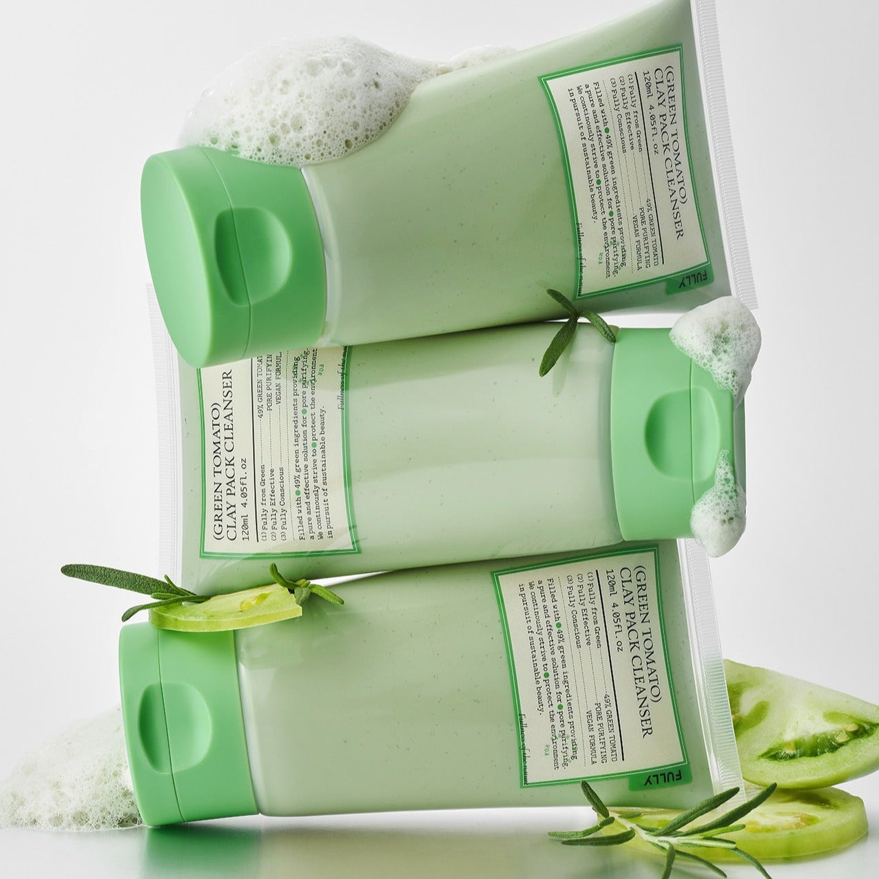 FULLY Green Tomato Clay Pack Cleanser 120ml bottles with green caps, surrounded by fresh rosemary and tomato slices.