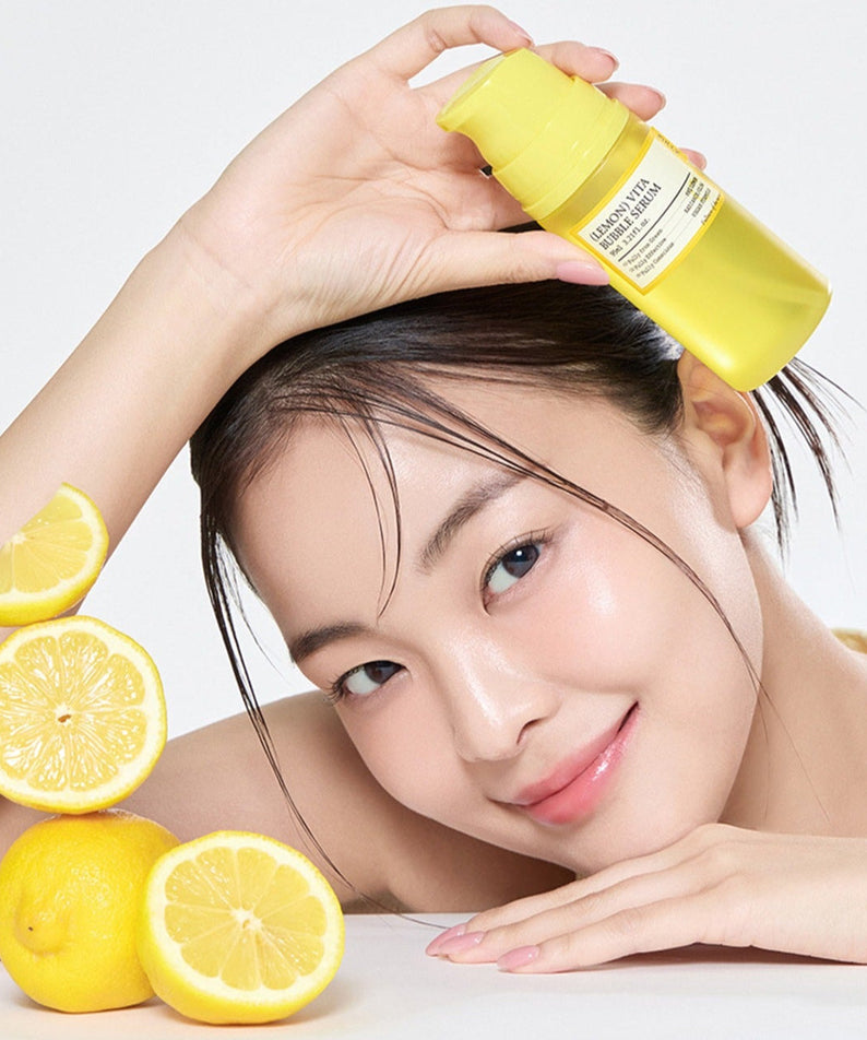 Smiling woman holding FULLY Lemon Vita Bubble Serum 95ml bottle, surrounded by fresh lemons, showcasing skincare benefits.