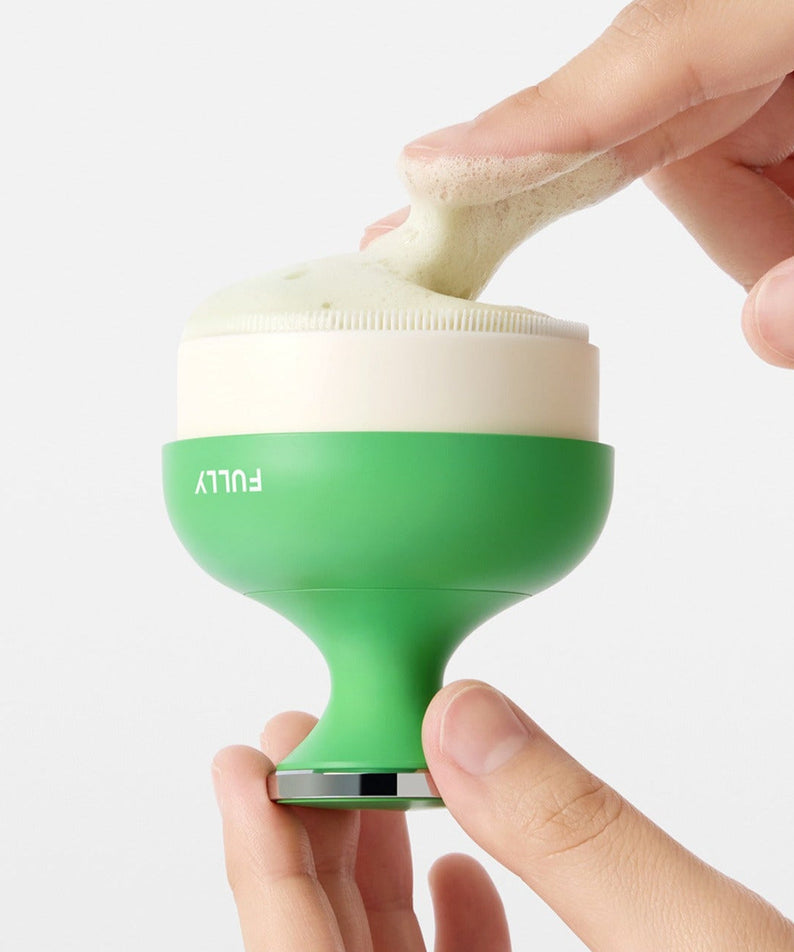 Hands using the FULLY Pore brush for gentle facial cleaning and exfoliation
