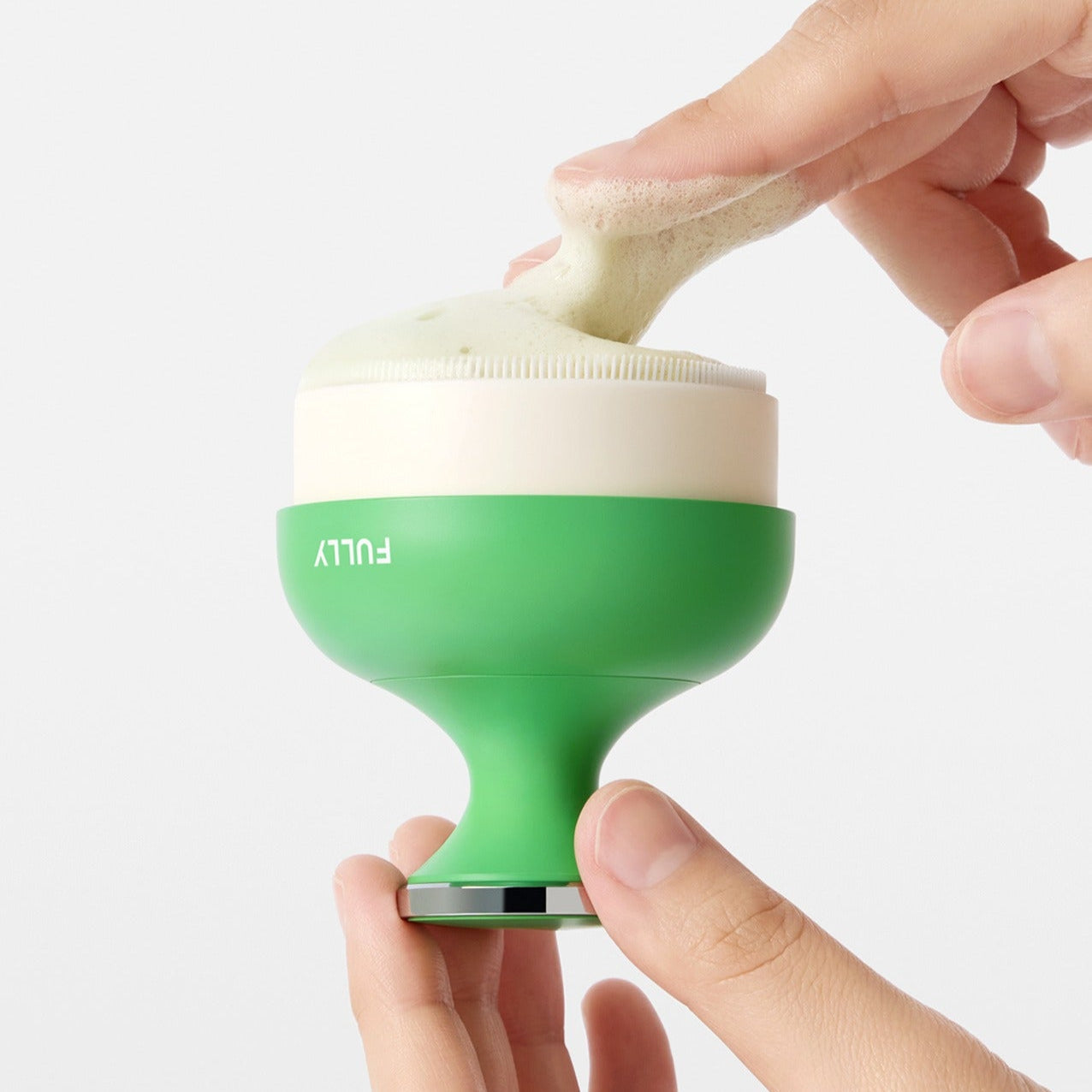 Hands using the FULLY Pore brush for gentle facial cleaning and exfoliation