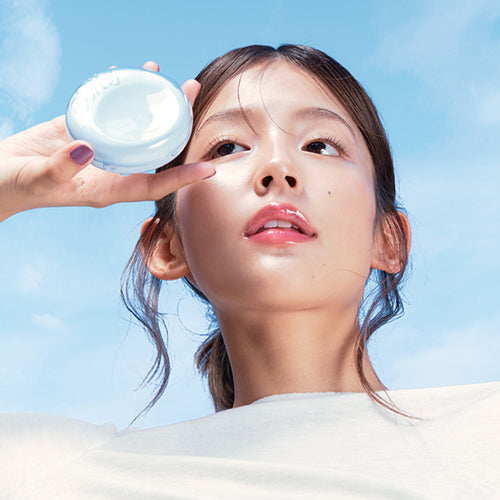 Woman holding FWEE Cushion Glass Natural product against a blue sky