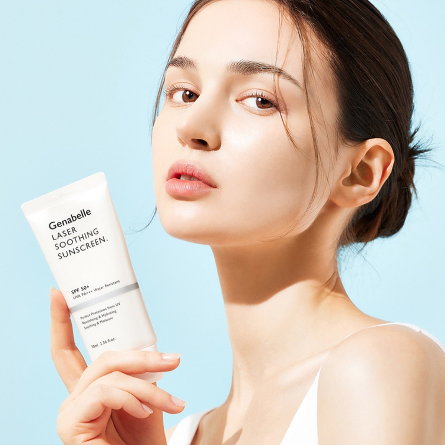 Woman holding GENABELLE Laser Soothing Sunscreen 70ml against a blue background