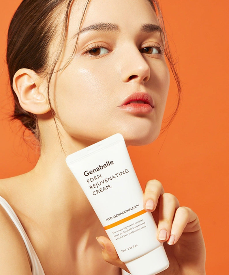 Woman holding GENABELLE PDRN Rejuvenating Cream 70ml against orange background.